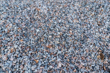Bulk of crushed rock or pebble rock, material for house building, that placed on the construction work site. Top view close-up, selective focus.