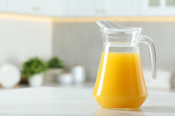 Tasty orange juice in jug on white marble table. Space for text