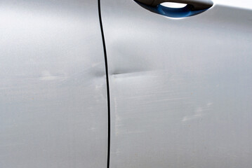 Scratch and dent on car door,  vehicle damage, often resulting from minor collisions or accidents....