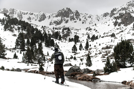 Close-up rear view of a skier skiing past a mountain river
