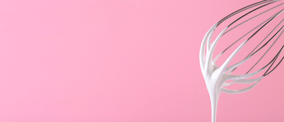 Whisk with beaten cream on pink background, closeup. Banner design, space for text