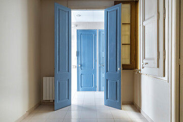 Bright hallway with blue doors allowing natural light to stream in, exhibiting a clean and minimalistic interior design that emphasizes elegance and simplicity.