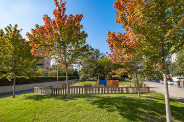Bright, vibrant park with children's playground featuring slides, benches, and surrounded by lush green grass and trees, perfect for community recreational activities Sant Cugat in Spain