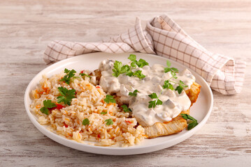 Chicken fillet under creamy mushroom sauce and rice aside