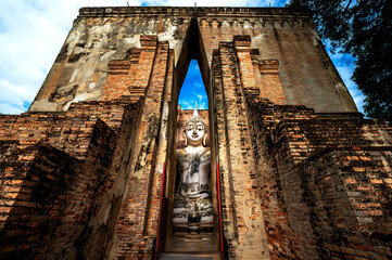 Naklejka premium Big buddha image with ruined historical landmark in Sukhothai, Thailand