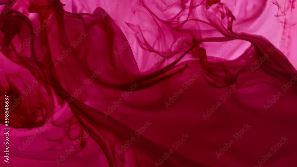 Aufkleber red ink swirls and mixes in a clear liquid, creating abstract patterns and colors.