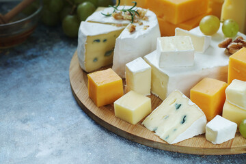 Several types of cheese served with honey and grapes