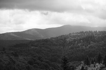 a disturbing black and white photo of the Bieszczady peaks with clouds above them and the sun breaking through the clouds