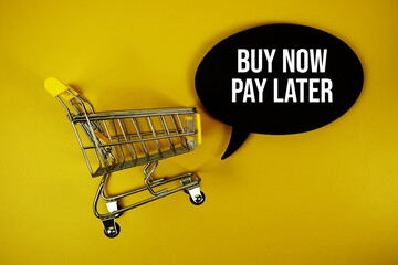 Buy Now Pay Later text on speech bubble with mini trolley shopping cart top view on yellow...