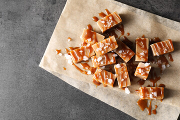 Tasty candies, caramel sauce and salt on grey table, top view. Space for text