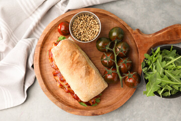 Tasty sandwich with bacon, tomatoes and spices on grey table, flat lay