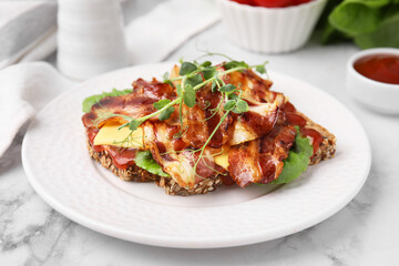 Tasty sandwich with bacon and microgreens on white marble table, closeup