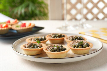 Delicious canapes with pate and capers on white table