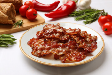 Slices of tasty fried bacon, tomatoes, different spices and bread on white table