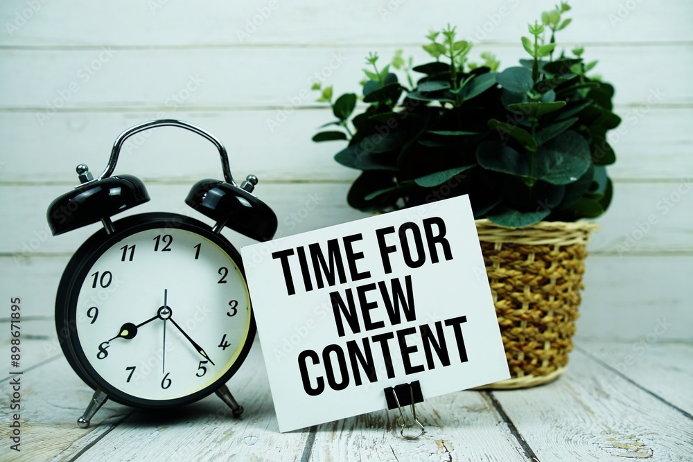 Poster time for new content text on paper card with alarm clock on wooden background