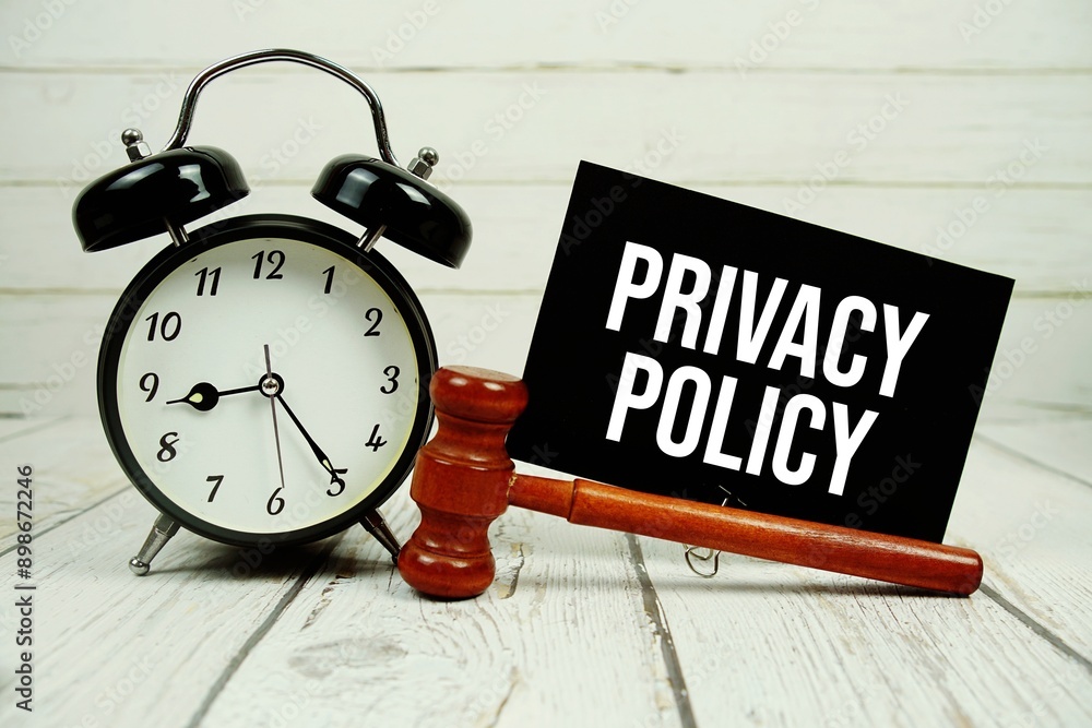 Poster privacy policy text on paper card with alarm clock and wooden judge gavel on wooden background