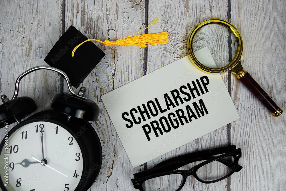 Poster scholarship program text on paper card with alarm clock and magnifying glass top view on wooden back