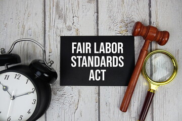 Fair Labor Standards Act text on paper card with alarm clock and wooden judge gavel top view on...