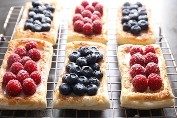 Tasty puff pastries with berries on grey table, closeup
