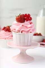 Tasty cupcakes with strawberries and red currants on white table, closeup