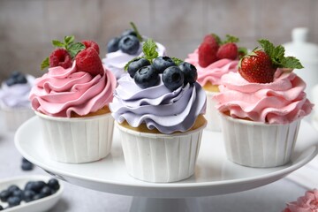 Tasty cupcakes with different berries on light grey table, closeup