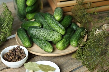 Fresh cucumbers, dill and spices on wooden table, closeup. Preparation for pickling