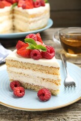 Piece of tasty sponge cake with fresh berries and mint served on wooden table, closeup