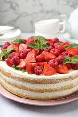 Tasty sponge cake with fresh berries and mint on light gray table, closeup