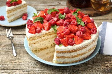 Tasty sponge cake with fresh berries and mint on wooden table, closeup