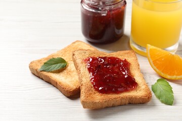 Delicious toasted bread slices with jam served on white wooden table