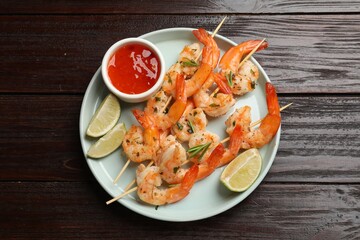 Skewers with delicious grilled shrimps served on wooden table, top view