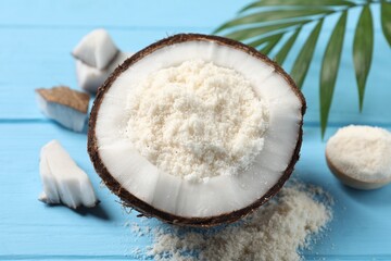 Fresh coconut flour, nuts and palm leaf on light blue wooden table