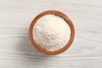 Fresh coconut flour in bowl on white wooden table, top view
