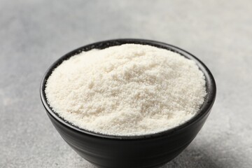 Coconut flour in bowl on light grey table, closeup