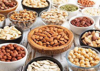Mixed raw nuts and seeds in bowls on kitchen table.Peanut,hazelnut,walnut,almonds,pistachio,sunflower,pumpkin,chia and cashew.Macro