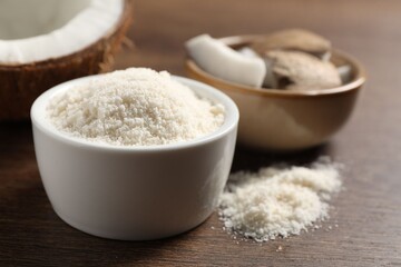 Organic coconut flour in bowl on wooden table, closeup