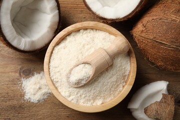 Coconut flour in bowl, scoop and fresh fruits on wooden table, flat lay