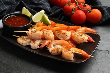 Skewers with delicious grilled shrimps served on black table