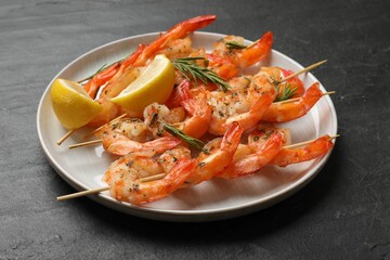Skewers with delicious grilled shrimps served on black table, closeup