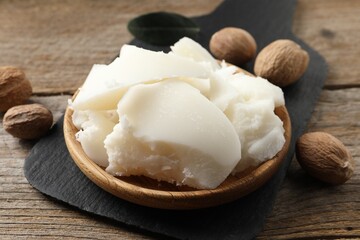 Fototapeta premium Natural shea butter and nuts on wooden table, closeup