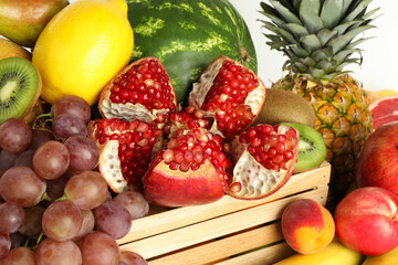 Wooden crate with many different fresh fruits on white background