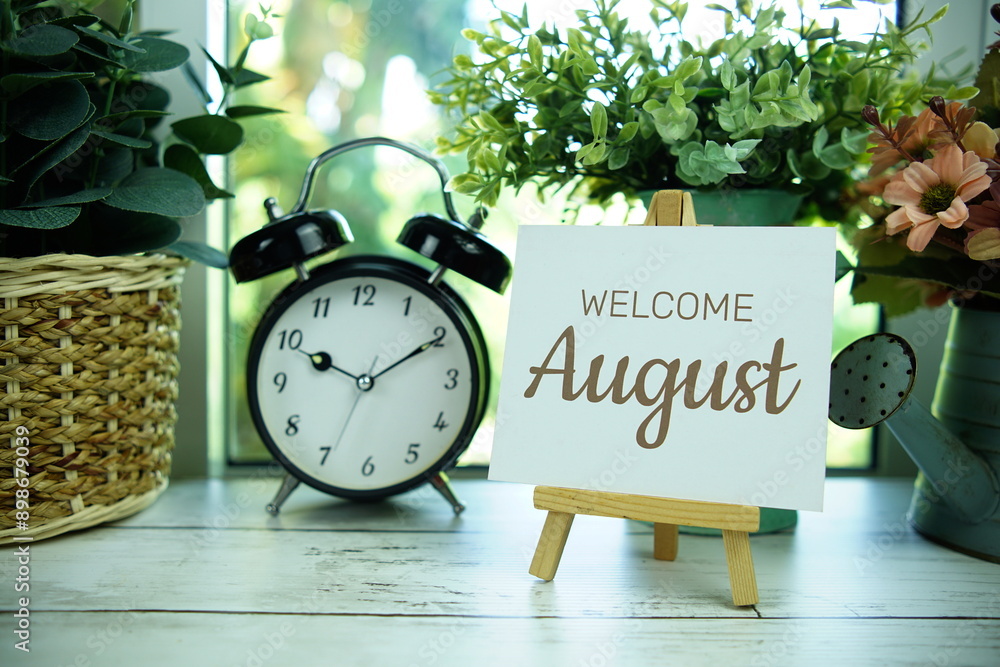 Poster welcome august text on paper card with easel and alarm clock in the window background