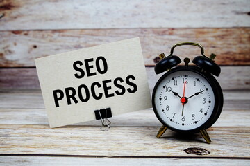 SEO Process text on paper card with alarm clock on wooden background