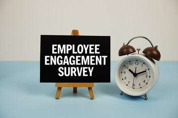 Employee Engagement Survey text on paper card with alarm clock on blue background