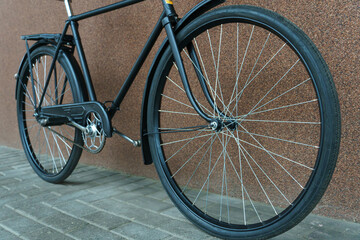 An old classic bike on a wall background. Bicycle repair. A black bicycle after restoration. Details of the bike in close-up.