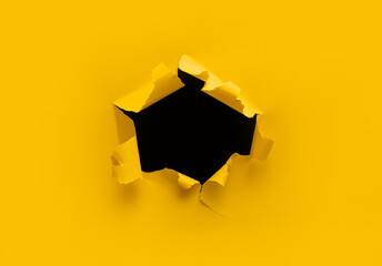 Torn hole in yellow paper with black empty background. Copy space, mockup. Place for text or logo.