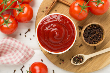 Delicious ketchup with spices and tomatoes on wooden background, top view
