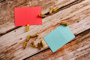 red and blue empty notes with scattered 9 mm bullet ammunition on wood plank background
