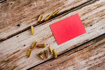 red empty note with scattered 9 mm bullet ammunition on wood plank background