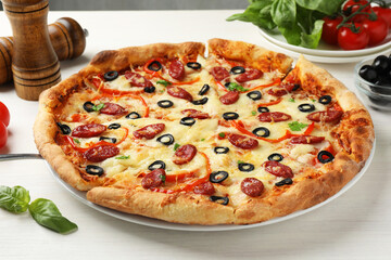 Tasty pizza with smoked sausages, olives, pepper and parsley on light wooden table, closeup